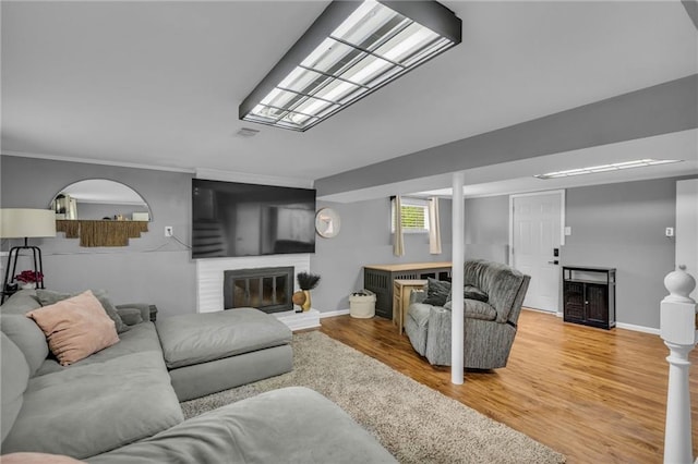 living area with crown molding, baseboards, wood finished floors, and a fireplace