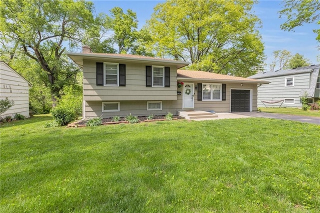 tri-level home featuring a garage, a chimney, a front lawn, and aphalt driveway