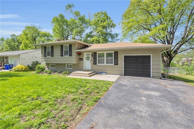 split level home with driveway, a chimney, a front yard, a garage, and fence
