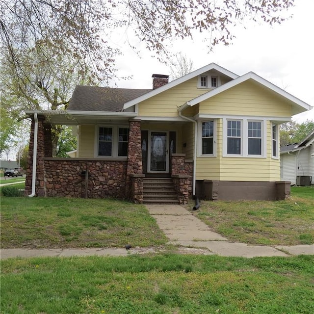 101 E 3rd St, Stanberry, MO 64489 - view of front of property featuring a chimney, a porch, central air condition unit, stone siding, and a front lawn