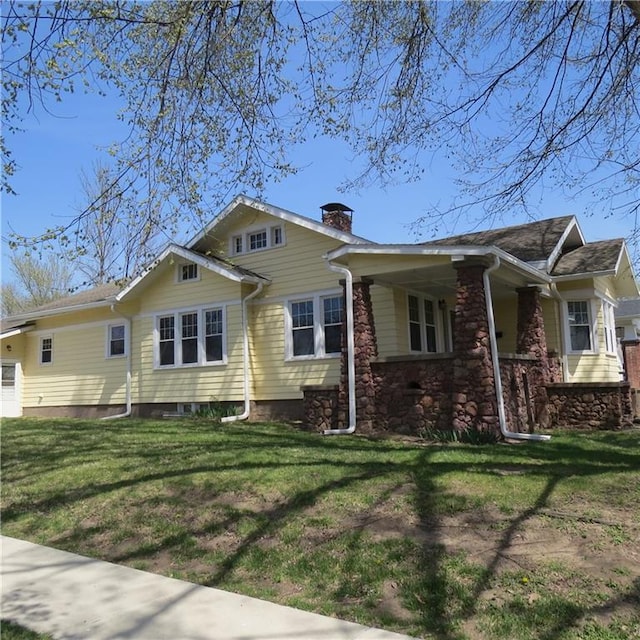 101 E 3rd St, Stanberry, MO 64489 - view of front of house with a chimney, covered porch, a front lawn, and stone siding