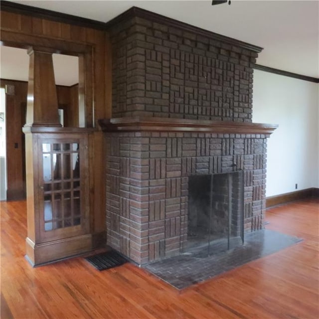 101 E 3rd St, Stanberry, MO 64489 - room details with baseboards, wood finished floors, ornamental molding, and a brick fireplace