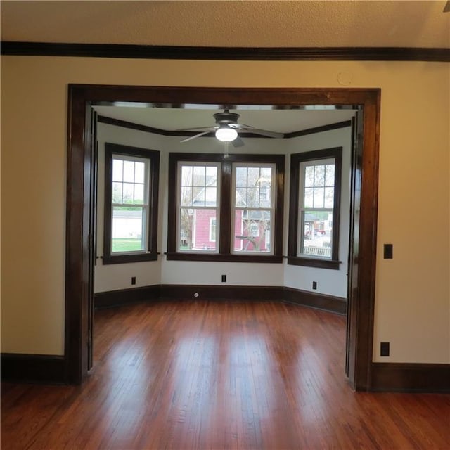 101 E 3rd St, Stanberry, MO 64489 - spare room with dark wood finished floors, baseboards, ornamental molding, and a ceiling fan