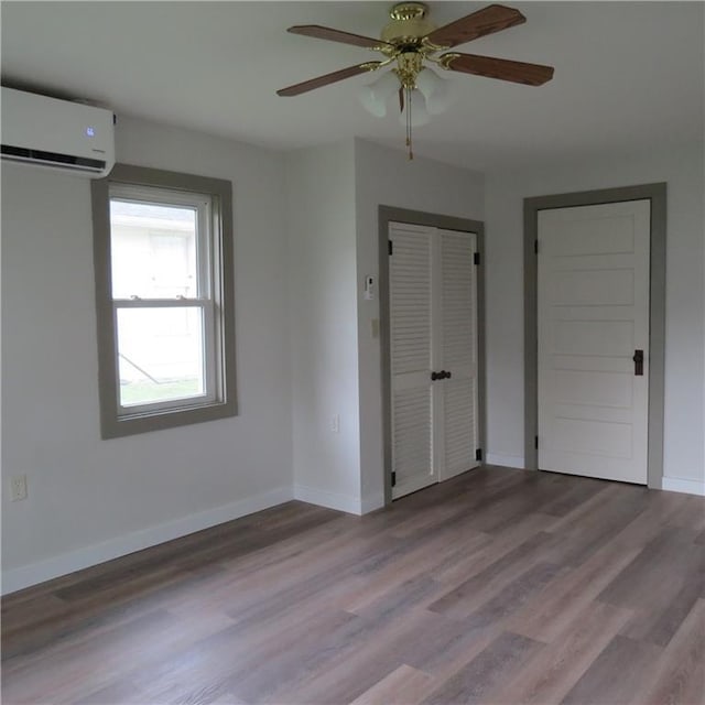 101 E 3rd St, Stanberry, MO 64489 - unfurnished bedroom with wood finished floors, a wall unit AC, a ceiling fan, and baseboards
