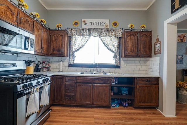 402 E Walnut St, Independence, MO 64050 - kitchen featuring appliances with stainless steel finishes, a sink, light wood-style floors, light countertops, and ornamental molding