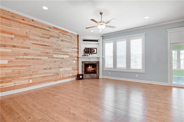 unfurnished living room with a ceiling fan, ornamental molding, wood finished floors, a stone fireplace, and recessed lighting