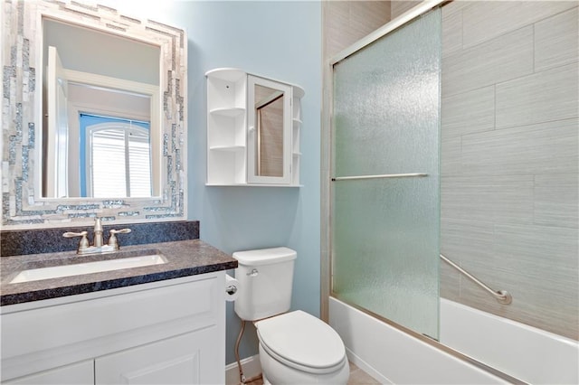 full bathroom featuring toilet, vanity, and bath / shower combo with glass door