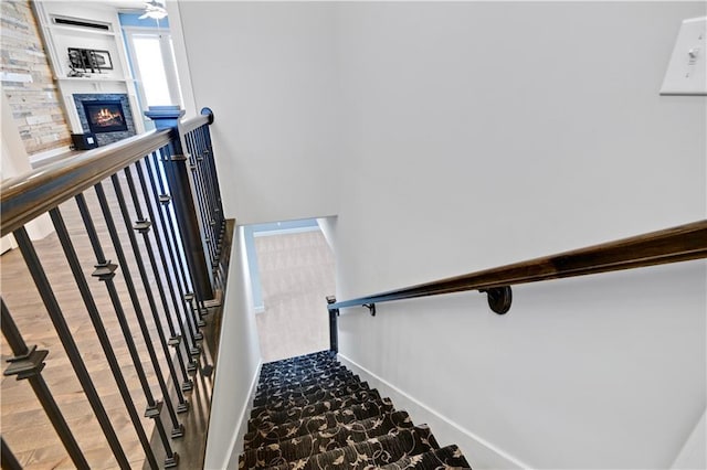 stairs featuring baseboards and a stone fireplace