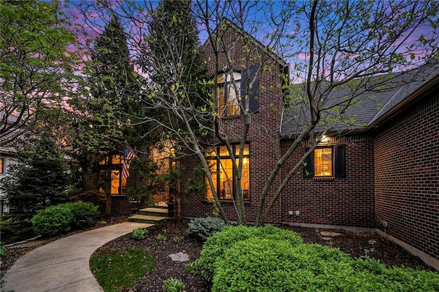 back of property at dusk with brick siding