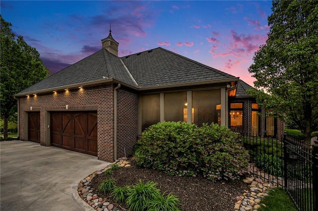 view of front of house featuring brick siding, driveway, fence, and a garage