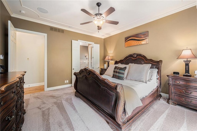carpeted bedroom featuring visible vents, crown molding, baseboards, ceiling fan, and ensuite bath