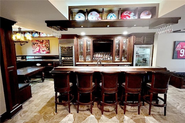 bar with bar, stone finish flooring, refrigerator, a sink, and wine cooler