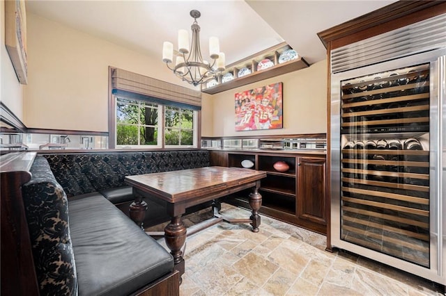 interior space featuring stone tile floors, a chandelier, and wine cooler