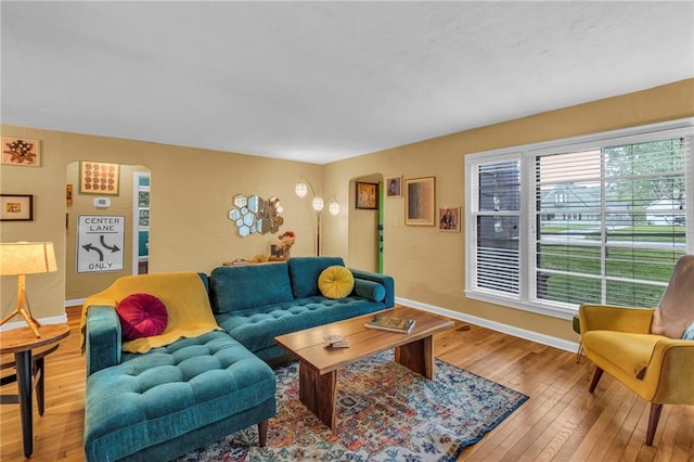 living room with hardwood / wood-style floors, baseboards, and arched walkways