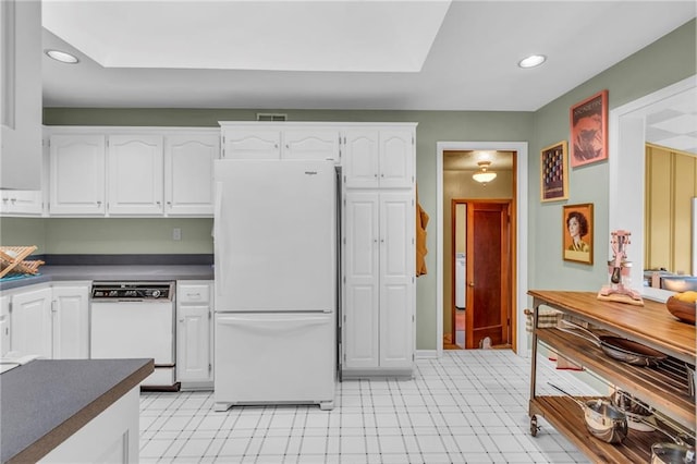 kitchen featuring white appliances, white cabinets, dark countertops, recessed lighting, and light flooring