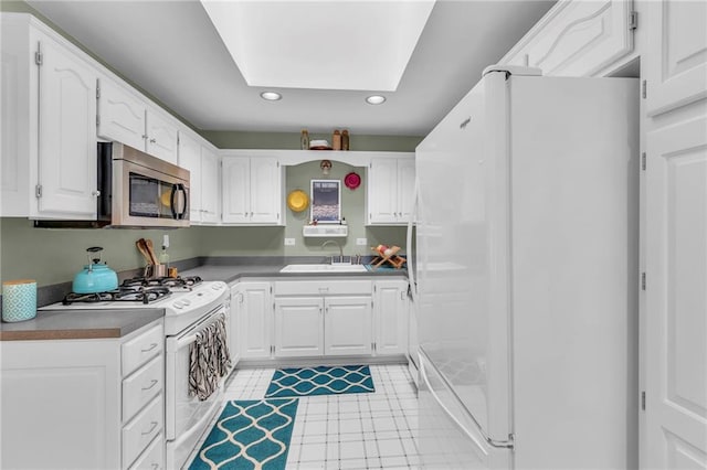 kitchen with white appliances, a sink, recessed lighting, white cabinetry, and light tile patterned floors