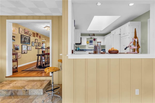 kitchen with freestanding refrigerator, a skylight, and a peninsula