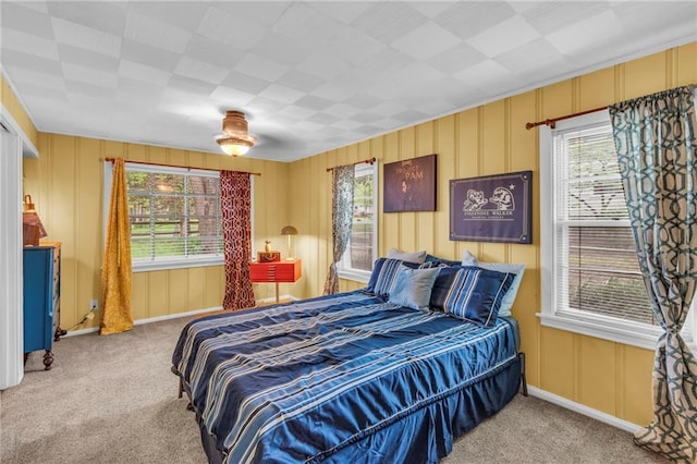 bedroom featuring carpet floors, baseboards, and a decorative wall