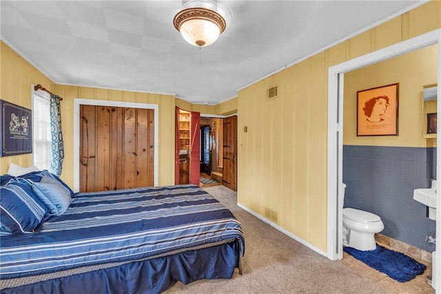 carpeted bedroom featuring ornamental molding and ensuite bath