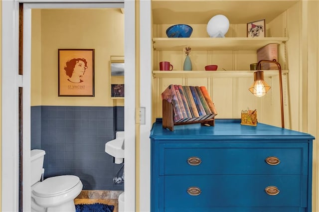 bathroom with toilet, tile walls, and wainscoting