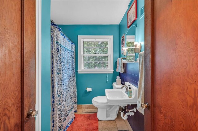 full bathroom featuring a sink, toilet, baseboards, and curtained shower