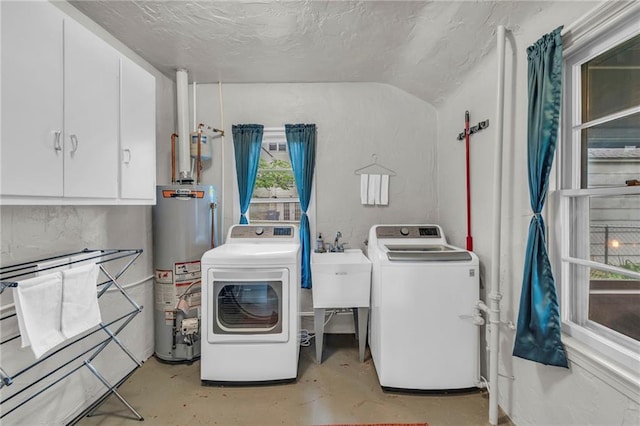 washroom featuring water heater, cabinet space, washer and dryer, and a textured ceiling
