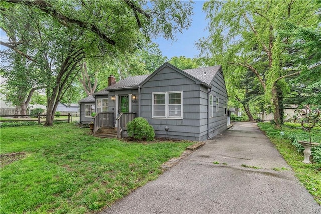 bungalow featuring a chimney and asphalt driveway