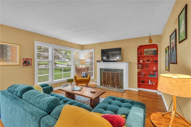 living room featuring wood finished floors, a tile fireplace, and baseboards