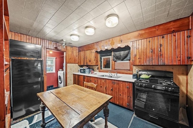 6425 N Edison Ave, Kansas City, MO 64151 - kitchen featuring a sink, black range with gas stovetop, washer / dryer, brown cabinetry, and wood walls