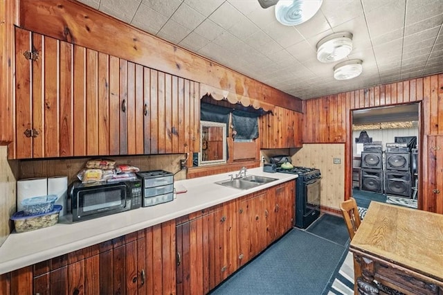 6425 N Edison Ave, Kansas City, MO 64151 - kitchen with a sink, wood walls, light countertops, black appliances, and brown cabinetry
