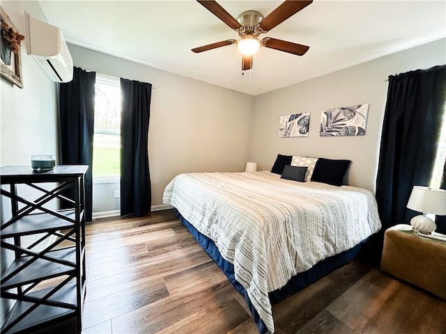 58 E Sugar Lake Cv, Mound City, KS 66056 - bedroom featuring wood finished floors, a wall unit AC, a ceiling fan, and baseboards