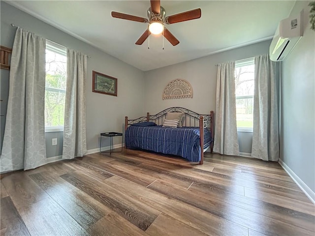 58 E Sugar Lake Cv, Mound City, KS 66056 - bedroom with an AC wall unit, multiple windows, a ceiling fan, and wood finished floors