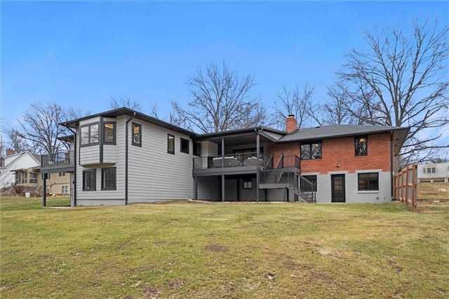 rear view of house featuring a chimney, a wooden deck, a lawn, and stairs