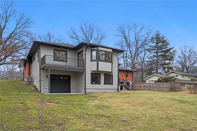 rear view of house with central air condition unit, a garage, a balcony, a yard, and fence