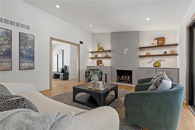 living room with visible vents, baseboards, light wood-type flooring, recessed lighting, and a fireplace
