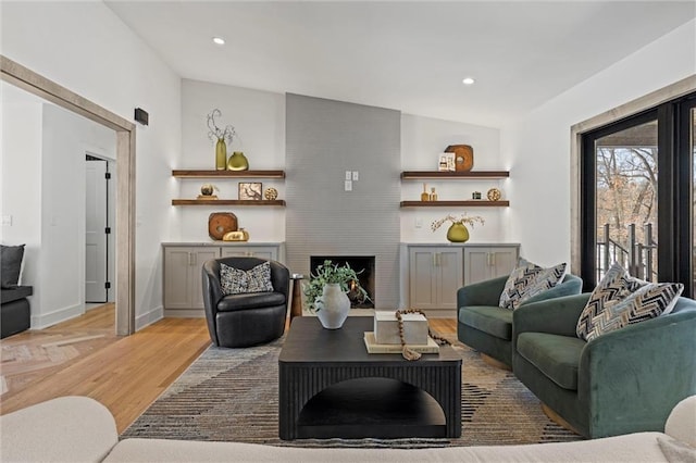 living area with a large fireplace, recessed lighting, light wood-style flooring, and baseboards
