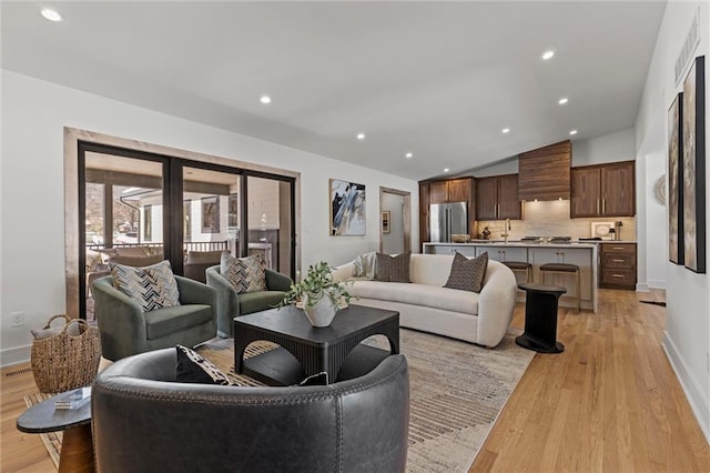 living room featuring light wood-type flooring, recessed lighting, vaulted ceiling, and baseboards