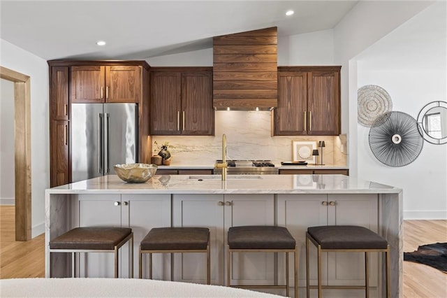 kitchen with premium range hood, a kitchen bar, high quality fridge, and decorative backsplash