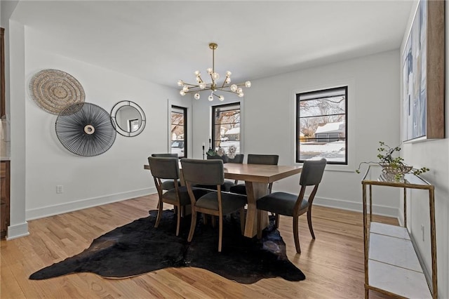 dining room featuring a chandelier, baseboards, and light wood-style floors