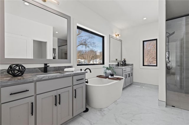 bathroom with two vanities, marble finish floor, a sink, a soaking tub, and a stall shower