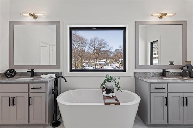 bathroom featuring a freestanding tub, two vanities, and a sink