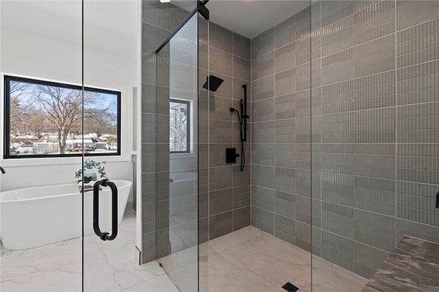 bathroom featuring a tile shower, a soaking tub, and marble finish floor