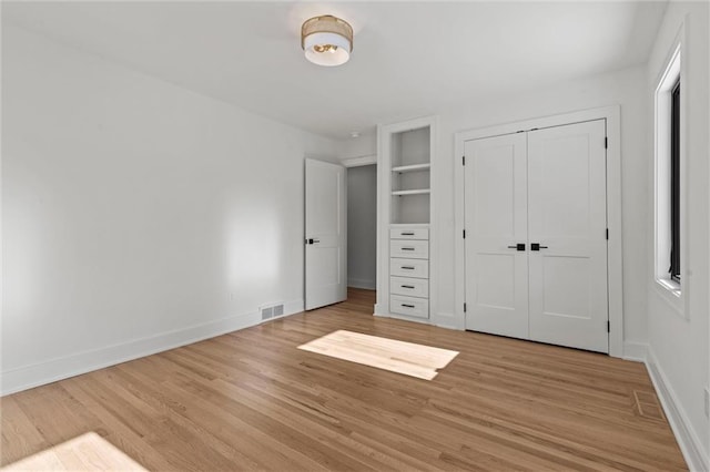 unfurnished bedroom with visible vents, a closet, light wood-style flooring, and baseboards