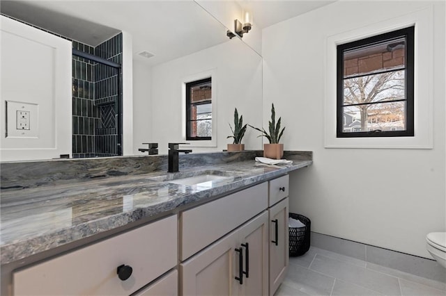 bathroom with toilet, vanity, tile patterned flooring, and baseboards
