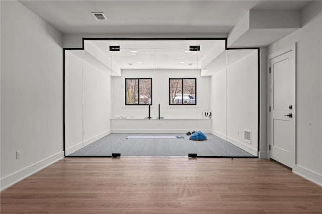 workout room with visible vents, wood finished floors, and baseboards