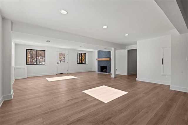 unfurnished living room with visible vents, light wood-type flooring, recessed lighting, and a brick fireplace