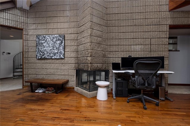 office featuring baseboards, wood finished floors, a high ceiling, and a fireplace