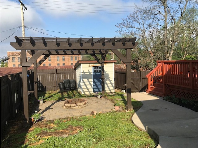 view of yard featuring a fenced backyard, a fire pit, a shed, and a wooden deck