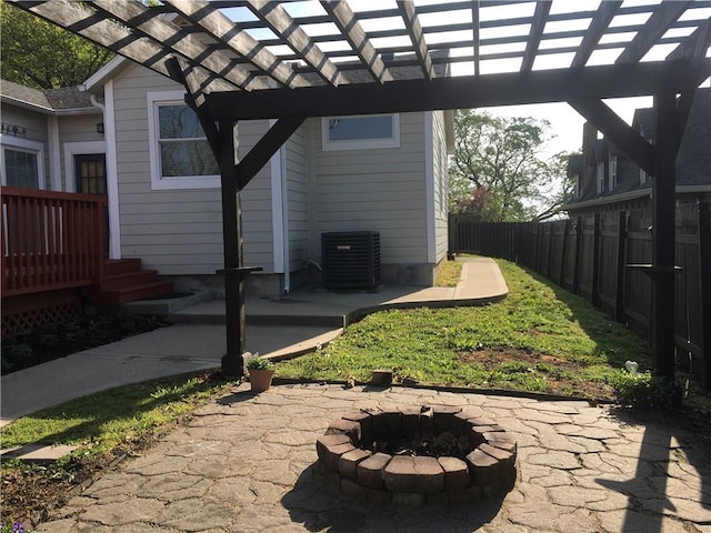 exterior space with a wooden deck, central AC, fence, a pergola, and a fire pit