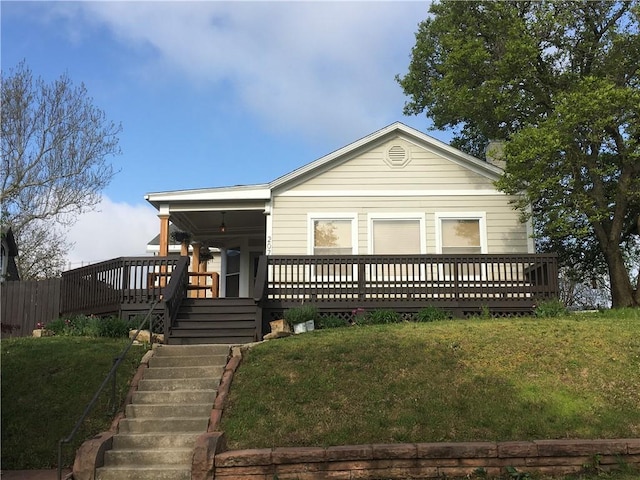 view of front of house featuring stairway, a wooden deck, and a front lawn